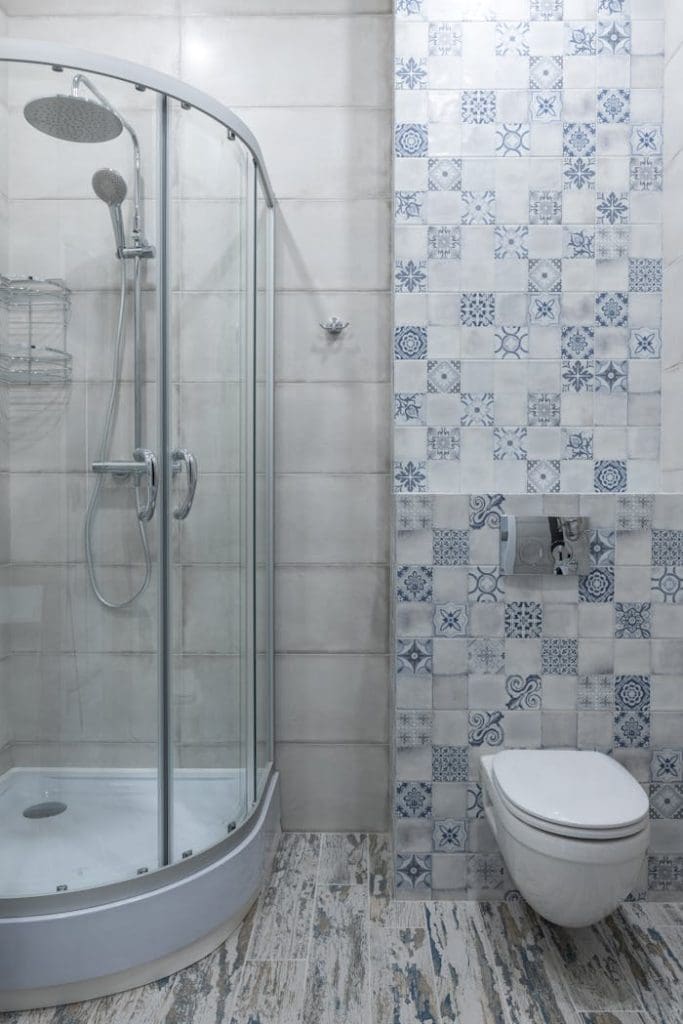 bathroom-with-glass-shower-cabin-6436789 Contemporary bathroom featuring a glass shower and patterned tile wall for a stylish look.